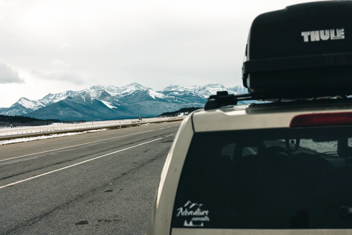 Car with a Thule roof box driving towards snowy mountains